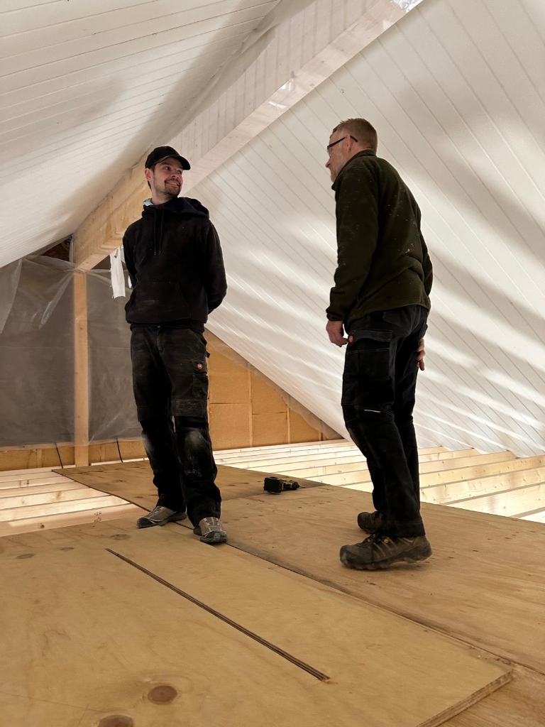 Andreas og Kim iført arbejdstøj på en byggeplads